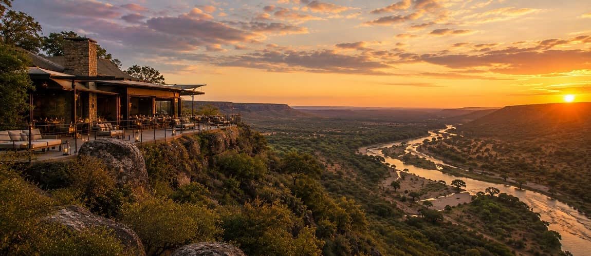 Singita Lebombo setting on the cliff tops. The river below glistens as the the rising sun causes reflection off its water.